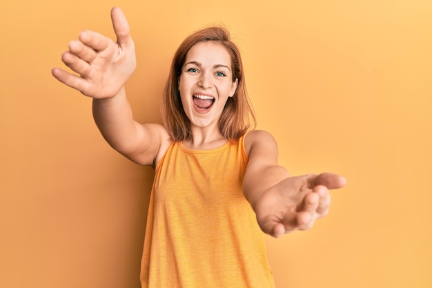 Young caucasian woman wearing casual style with sleeveless shirt looking at the camera smiling with open arms for hug. cheerful expression embracing happiness.