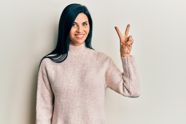 Young caucasian woman wearing casual winter sweater showing and pointing up with fingers number two while smiling confident and happy.