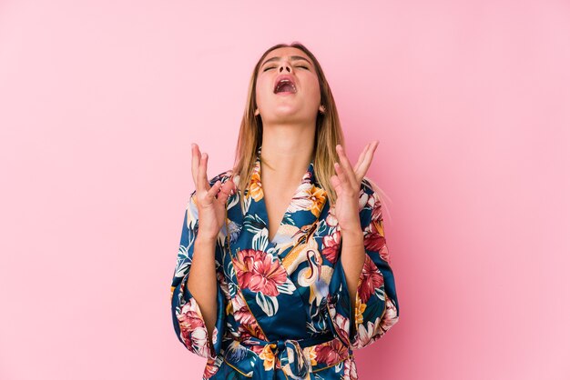 Young caucasian woman wearing pajamas screaming