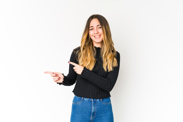 Young caucasian woman on white shocked pointing with index fingers to a copy space.