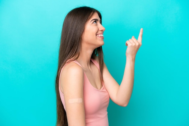 Young caucasian woman with band aids isolated on blue background intending to realizes the solution while lifting a finger up