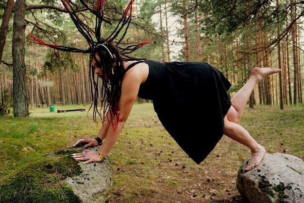 Young Caucasian woman with black and red punk hair posing in the forest