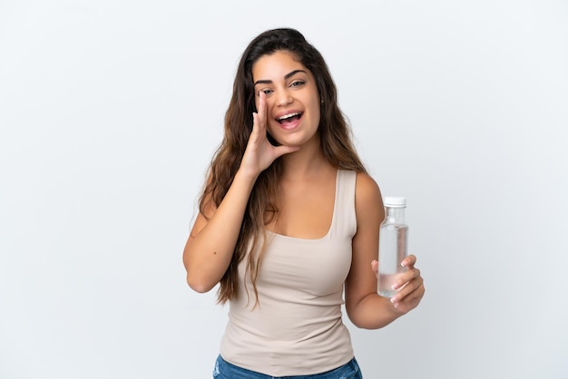 Young caucasian woman with a bottle of water isolated on white background shouting with mouth wide open