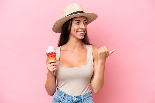 Young caucasian woman with a cornet ice cream isolated on pink background