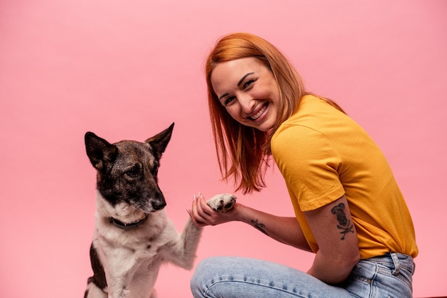 Young caucasian woman with his dog isolated on pink background