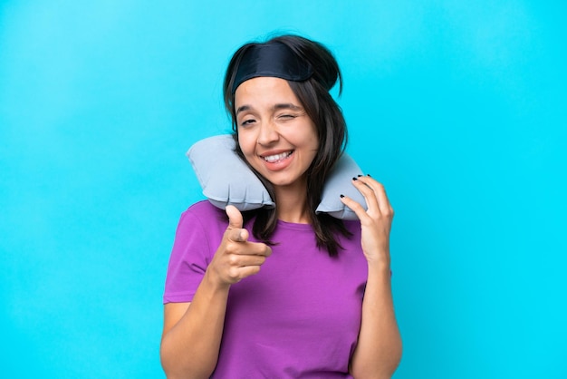 Young caucasian woman with Inflatable Travel Pillow isolated on blue background pointing to the front and smiling