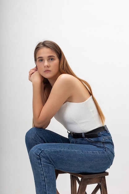 Young caucasian woman with long brown hair in in corset, blue jeans at studio