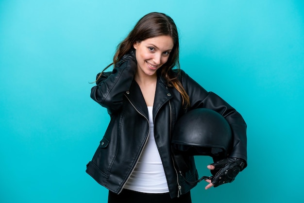 Young caucasian woman with a motorcycle helmet isolated on blue background laughing