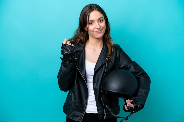 Young caucasian woman with a motorcycle helmet isolated on blue background making money gesture