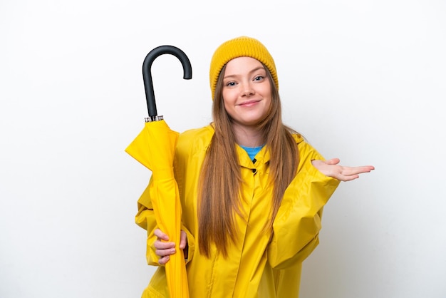 Young caucasian woman with rainproof coat and umbrella isolated on white background having doubts while raising hands