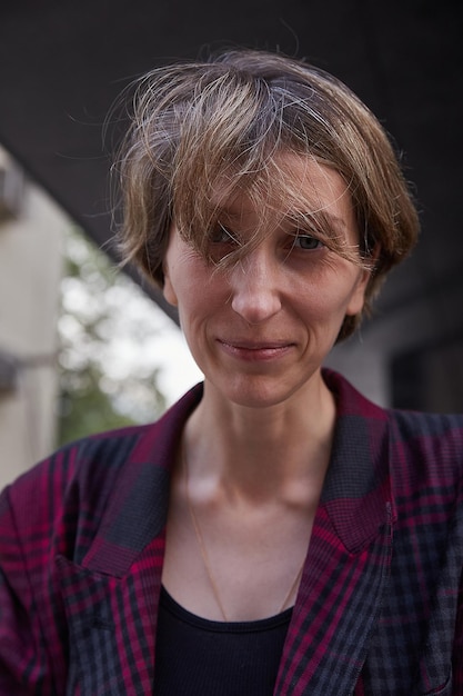 Young caucasian woman with short hair in red checkered jacket outdoors at street