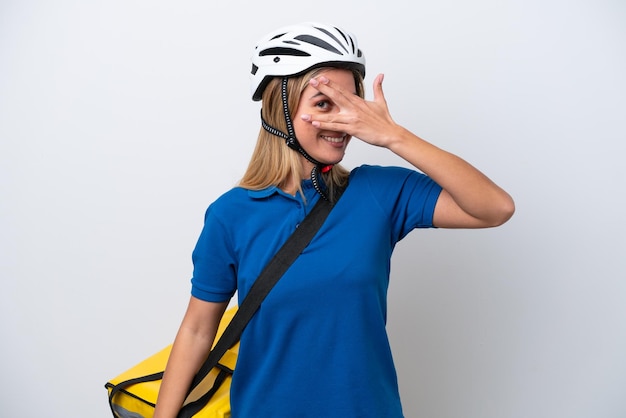 Young caucasian woman with thermal backpack isolated on white background covering eyes by hands and smiling