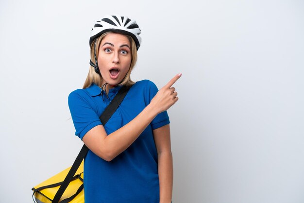 Young caucasian woman with thermal backpack isolated on white background surprised and pointing side