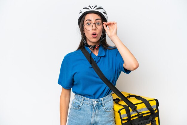 Young caucasian woman with thermal backpack isolated on white background with glasses and surprised