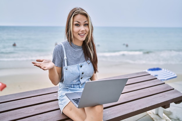 Young caucasian woman working using computer laptop outdoors celebrating achievement with happy smile and winner expression with raised hand