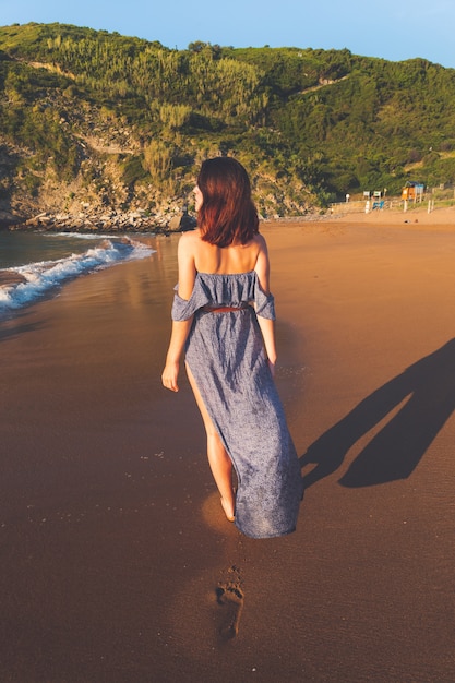 Young caucassian girl with a blue dress possing at Zarautz beach, Basque Country.