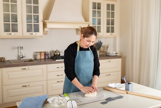 Young Central Asian woman cooking from dough in modern kitchen