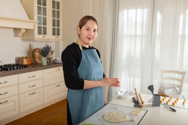 Young Central Asian woman is engaged in baking in the interior of a modern kitchen