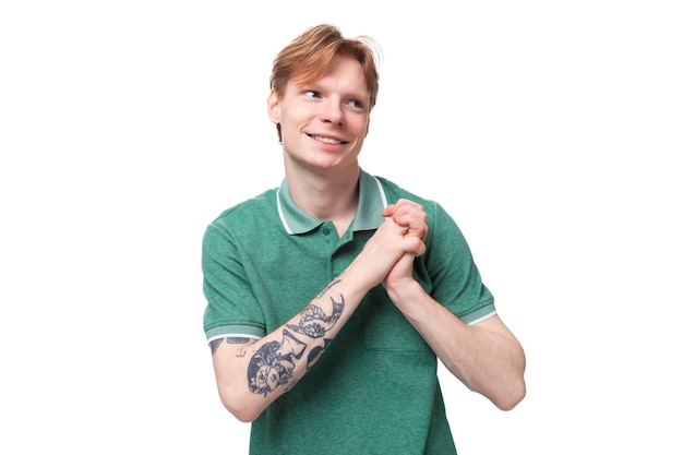 Photo young charming adorable ginger man with a tattoo on his arm dressed in a green short sleeve tshirt