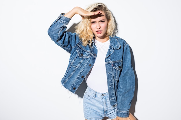 Young charming blonde look forward in a jeans jacket looks away isolated on white wall