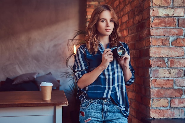 Young charming girl photographer stands in a room with a loft in