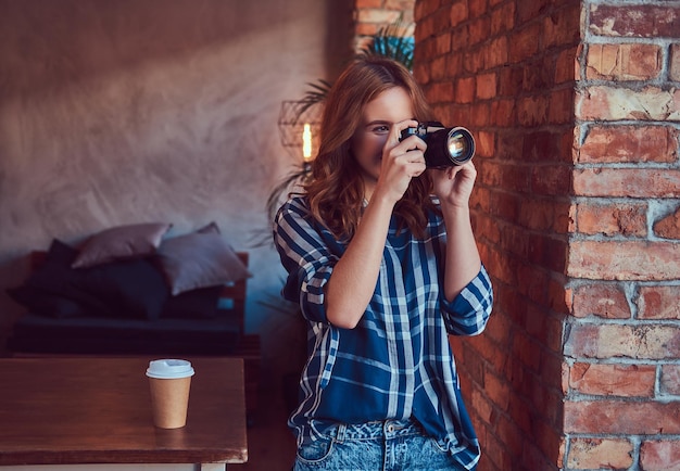 Young charming girl photographer stands in a room with a loft in