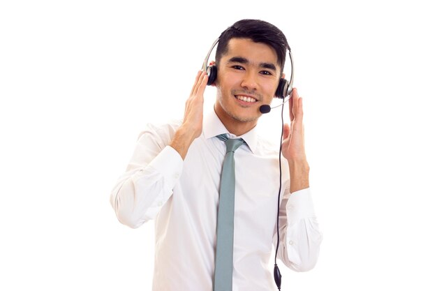 Young charming man with dark hair in white shirt with blue tie using headphones in studio