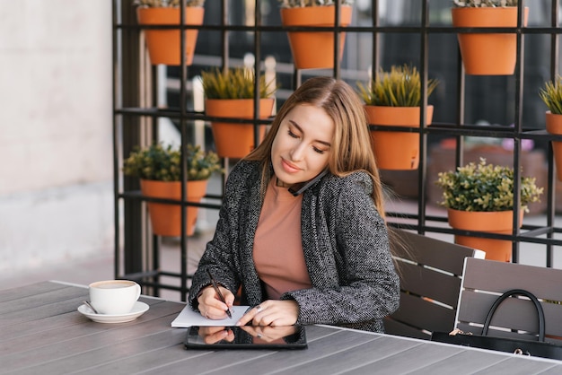 Young charming woman is calling on a mobile phone sitting in a cafe and talking on a mobile phone