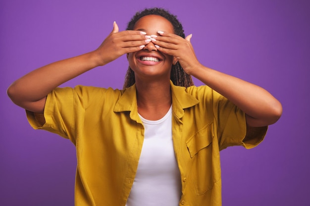 Young cheerful african american woman covers eyes with hands and smiling