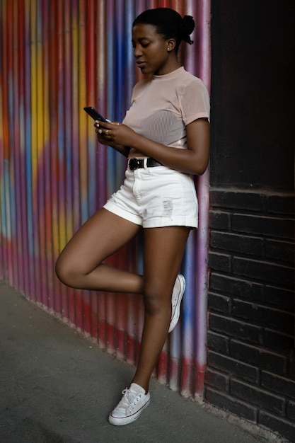 Young cheerful African American woman wears casual clothes hold in hand using mobile cell phone chat