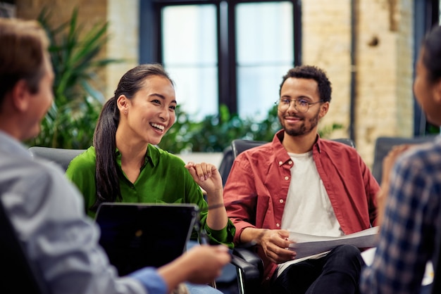 Young cheerful asian business woman discussing project results with colleagues while working