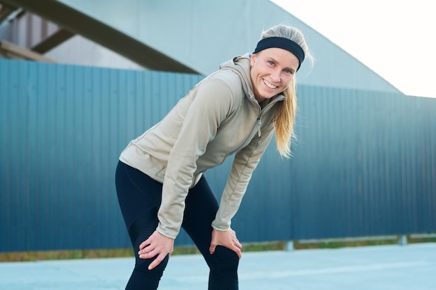 Young cheerful blond woman in activewear looking at camera with smile