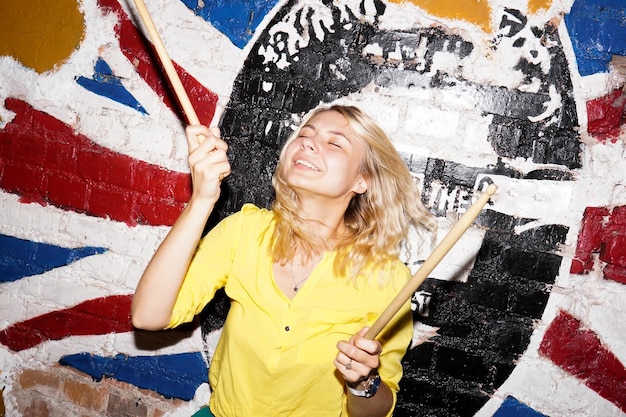 Young cheerful blonde plays a drum set for a computer game Party entertainment