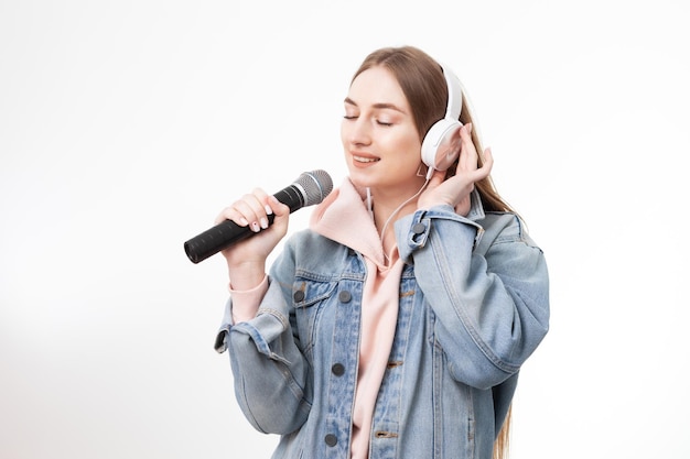 Young cheerful caucasian woman with headphones singing into microphone isolated on white background