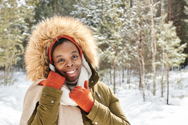 Young cheerful contemporary black woman in gloves winter jacket and scarf