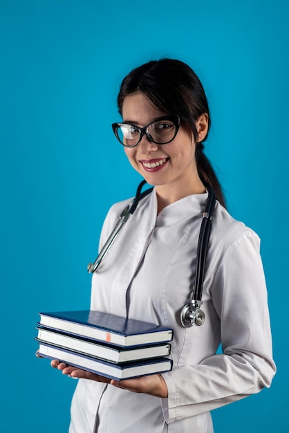 Young cheerful female doctor intern wearing glasses wearing health uniform holding books