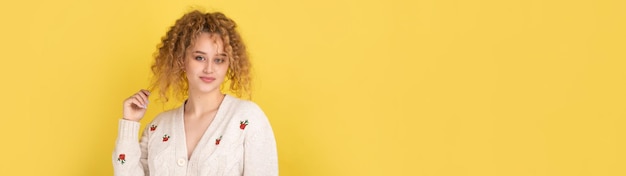 Young cheerful girl smiling at the camera while standing on a yellow background closeup