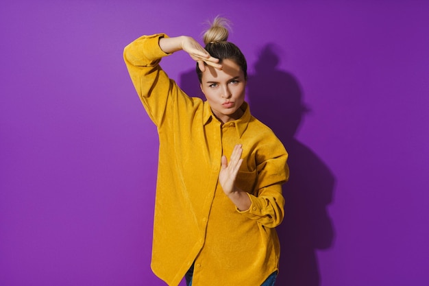 Young cheerful girl wearing yellow shirt dancing against purple background