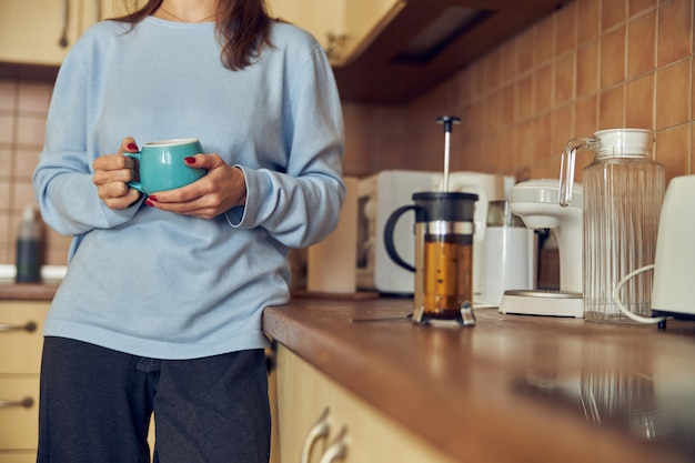 Young cheerful  and happy woman is preparing tasty tea  at her kitchen at home