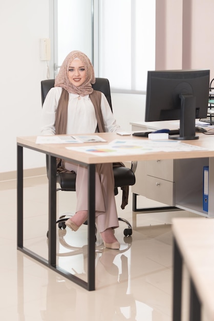 Young Cheerful Muslim Business Woman Working With Computer At Desk In The Modern Office And Talking On Phone