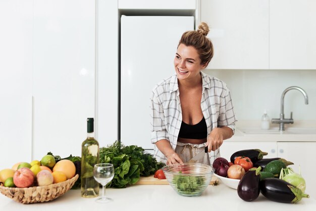 Photo young cheerful woman cooking healthy vegetarian dish at home