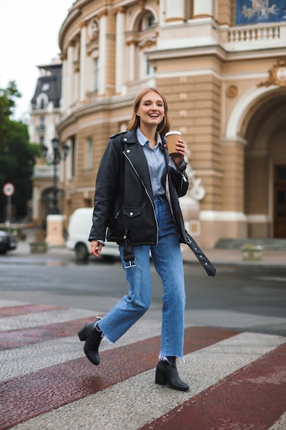 Young cheerful woman in leather jacket and jeans happily 