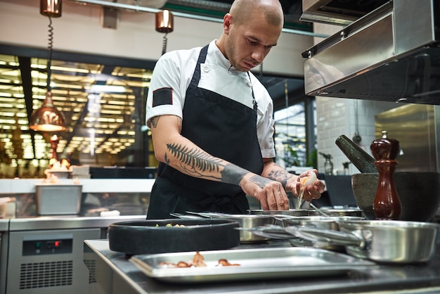 young chef breaking an egg for traditional italian pasta while standing in a restaurant kitchen