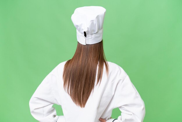 Young chef caucasian woman over isolated background in back position