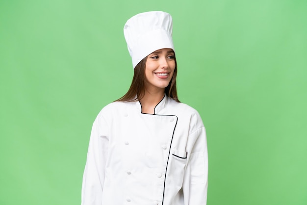 Young chef caucasian woman over isolated background looking side