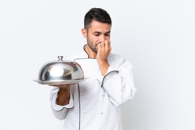 Young chef with tray isolated on white background having doubts