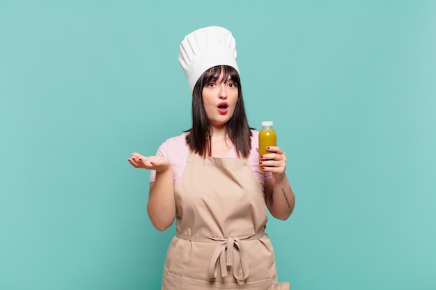 Young chef woman open-mouthed and amazed, shocked and astonished with an unbelievable surprise