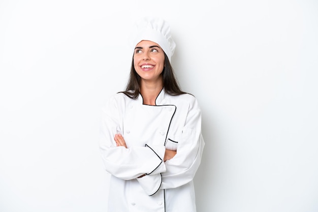 Young chef woman over white background looking up while smiling