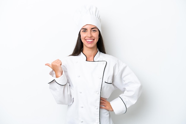 Young chef woman over white background pointing to the side to present a product