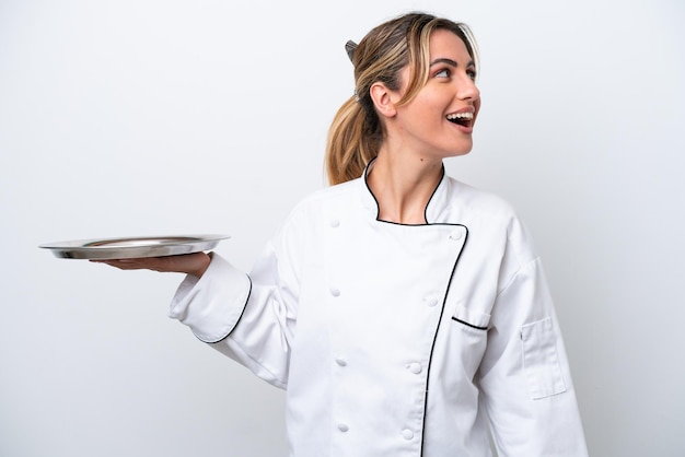 Young chef woman with tray isolated on white background laughing in lateral position